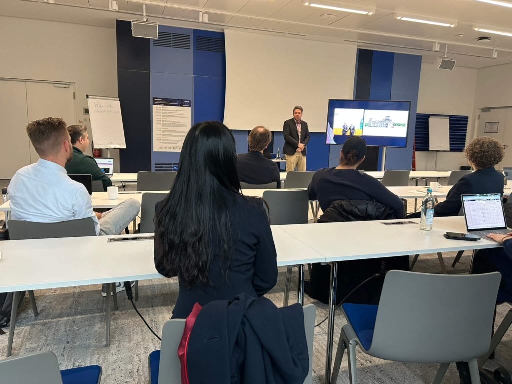 Business presentation in a conference room with attendees seated and a presenter speaking at a podium