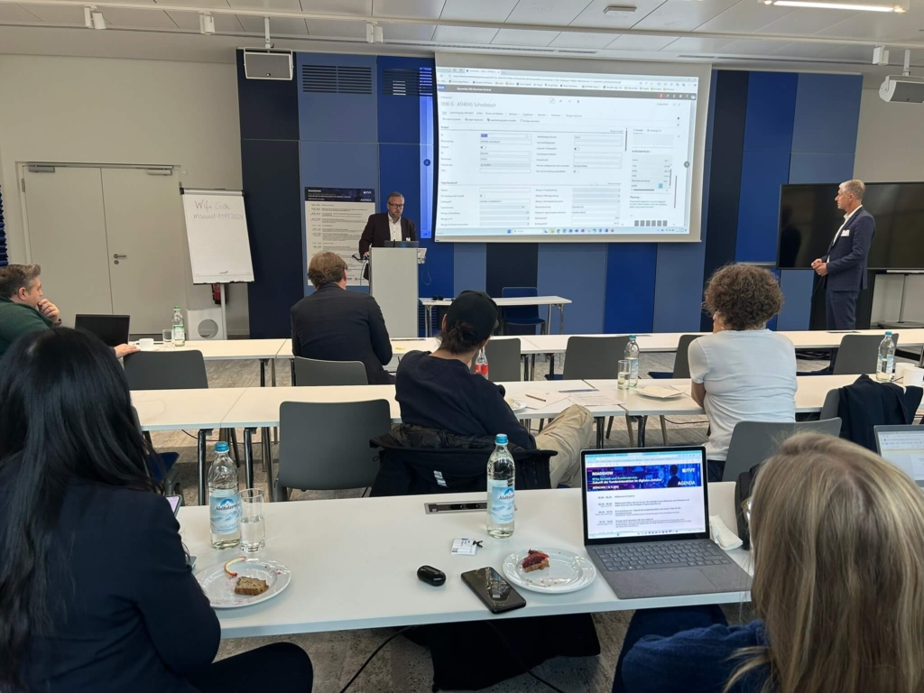 Business presentation in a conference room with attendees seated and a presenter speaking at a podium