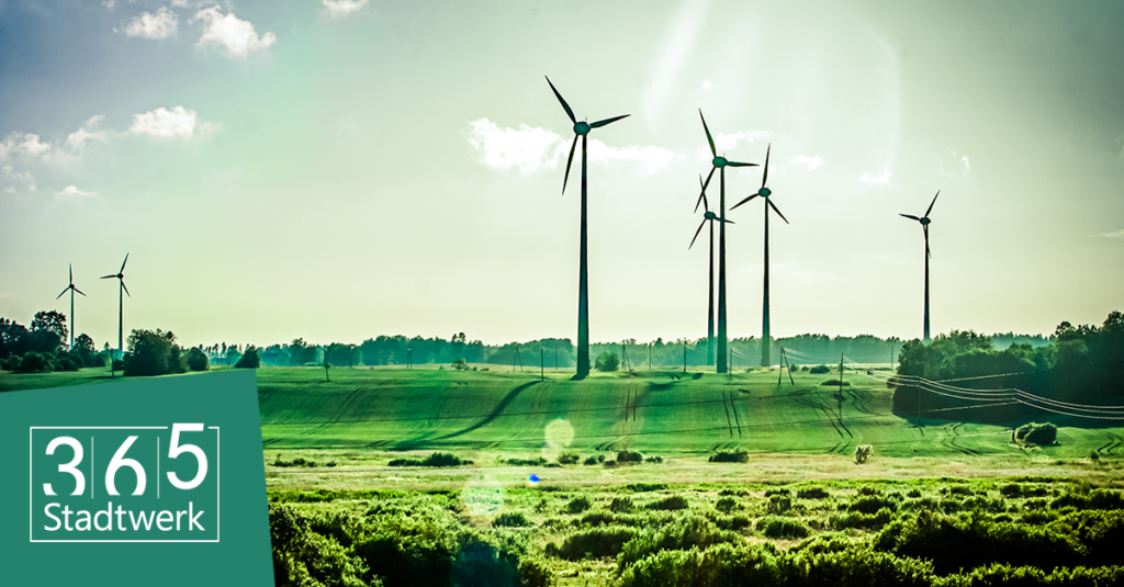 Grüne Landschaft mit mehreren Windkraftanlagen unter strahlend blauem Himmel, Logo „365 Stadtwerk“ in der unteren linken Ecke.